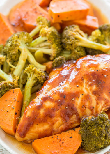 Glazed chicken breast with roasted broccoli and carrot slices on a white plate.