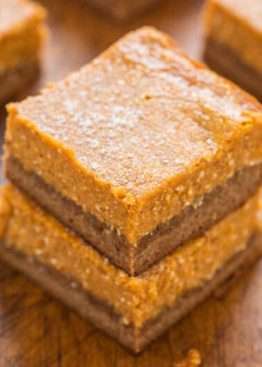 Stack of freshly baked pumpkin bars on a wooden surface.