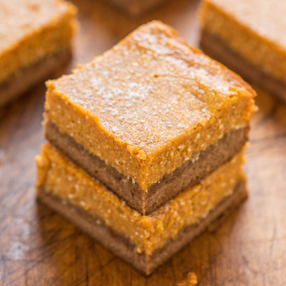 Stack of freshly baked pumpkin bars on a wooden surface.