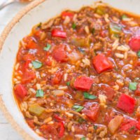 A bowl of hearty vegetable stew with chunks of tomato and sprinkled herbs.