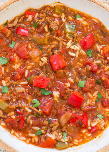 A bowl of hearty chili with rice, bell peppers, and herbs.
