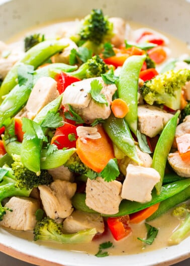 A stir-fry dish featuring chicken and assorted vegetables like broccoli, carrots, and snap peas in a light sauce.
