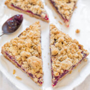 Slices of cranberry oatmeal bars on a white plate with a spoonful of jam on the side.