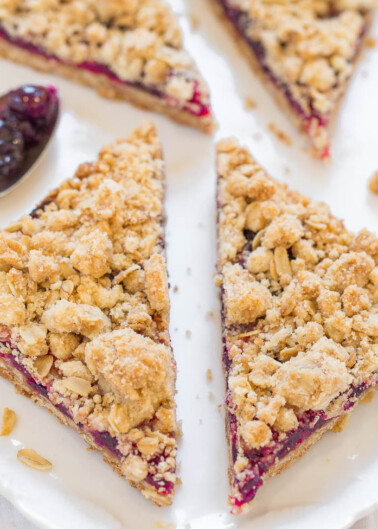 Slices of cranberry oatmeal bars on a white plate with a spoonful of jam on the side.