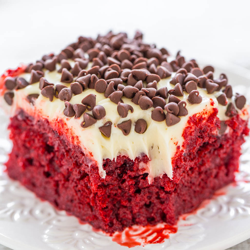 A slice of red velvet cake topped with cream cheese frosting and chocolate chips.