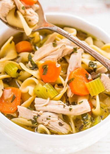 Bowl of chicken noodle soup with vegetables and a spoon.