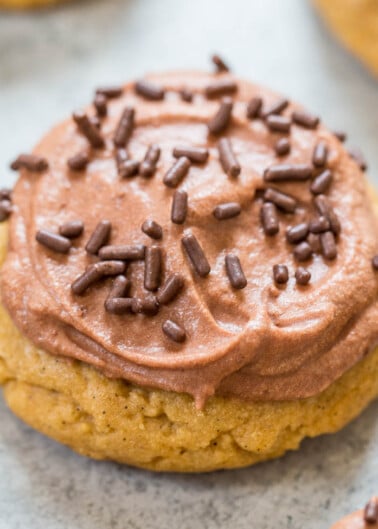 A freshly baked cookie topped with chocolate frosting and sprinkles.
