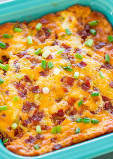 Baked casserole with melted cheese and bacon garnished with green onions in a blue baking dish.
