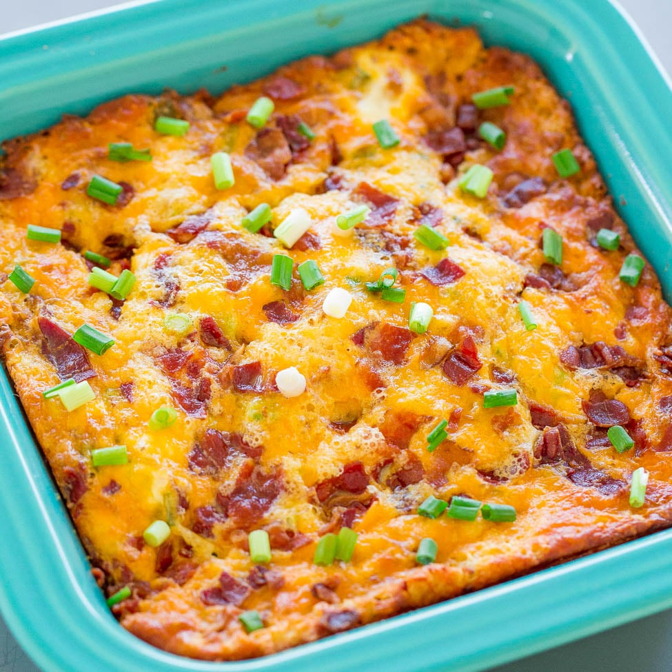 Baked casserole with melted cheese and bacon garnished with green onions in a blue baking dish.