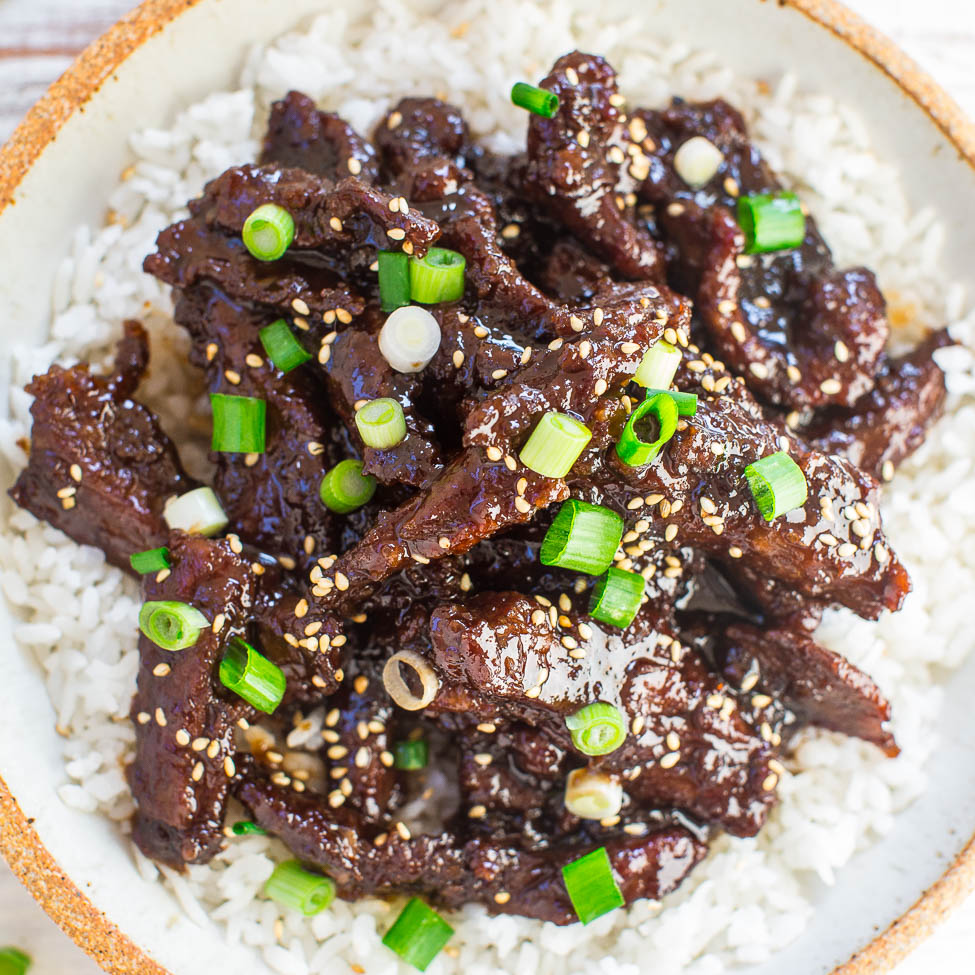 Korean beef bulgogi served over rice, garnished with green onions and sesame seeds.