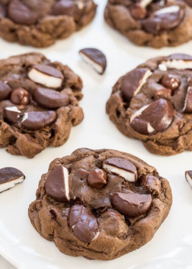 Freshly baked chocolate cookies with chocolate chunks on a white plate.