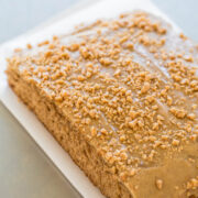A rectangular coffee cake topped with a glaze and crushed nuts.