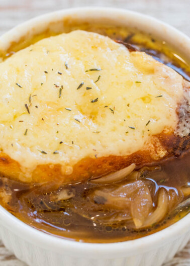 A bowl of french onion soup topped with melted cheese and garnished with herbs.