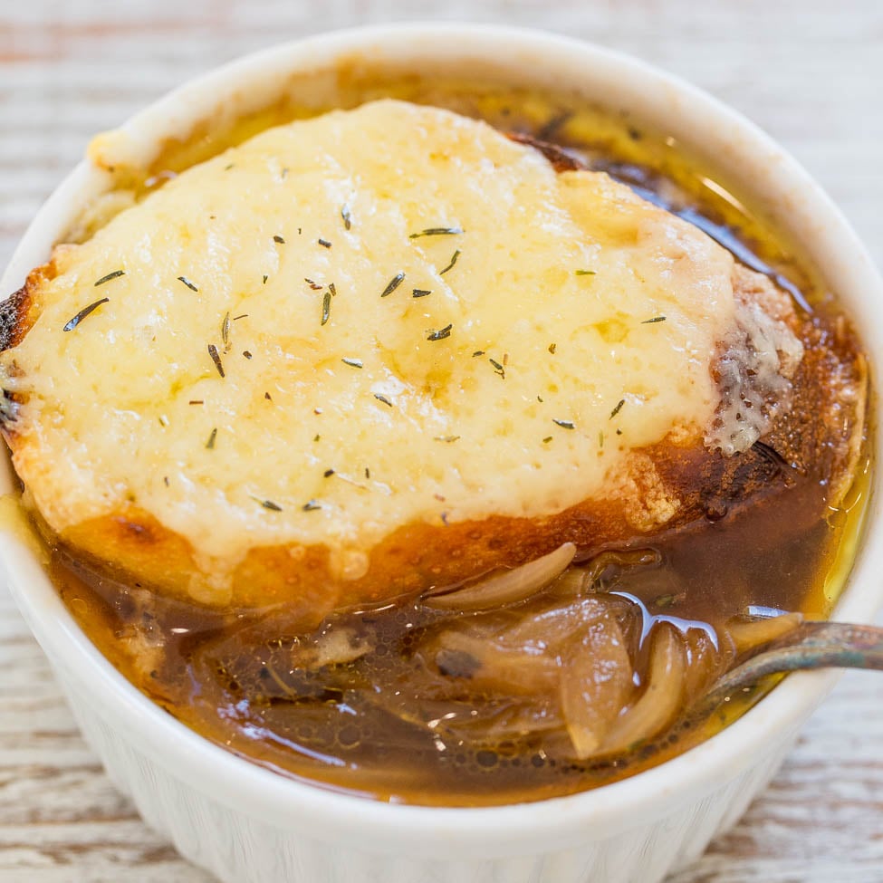 A bowl of french onion soup topped with melted cheese and garnished with herbs.