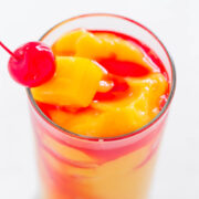 Glass of fruit punch garnished with a cherry.