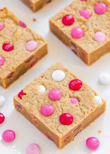 Blondie bars with pink and white m&m candies on a white plate.