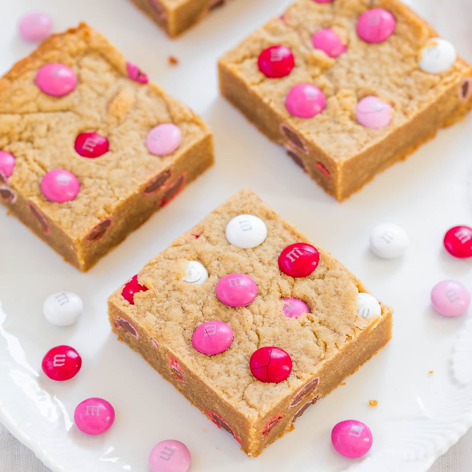 Blondie bars with pink and white m&m candies on a white plate.