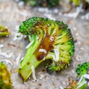 Roasted broccoli floret with melted cheese on a baking sheet.
