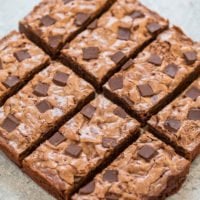Freshly baked chocolate chip brownies arranged in a grid pattern on a light surface.