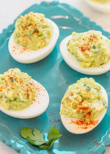 Three deviled eggs garnished with paprika on a blue plate.