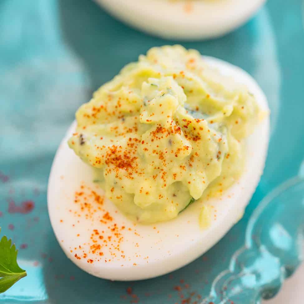 A deviled egg garnished with paprika on a turquoise plate.