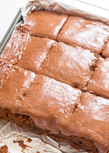 A tray of freshly baked brownies cut into squares, accompanied by a can of coca-cola.