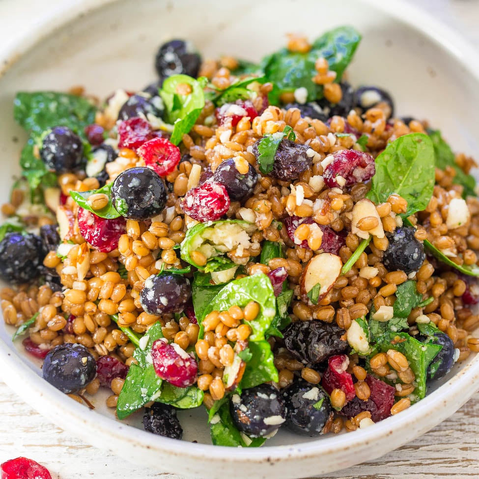 A bowl of wheat berry salad with spinach, feta, and mixed berries.