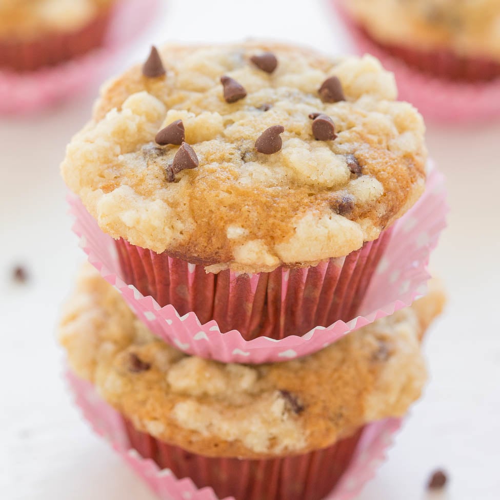 Three chocolate chip muffins in pink paper liners stacked in a column.