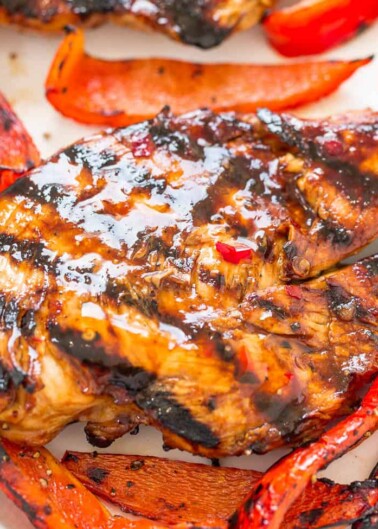 Grilled chicken breast with char marks served with roasted red bell peppers.