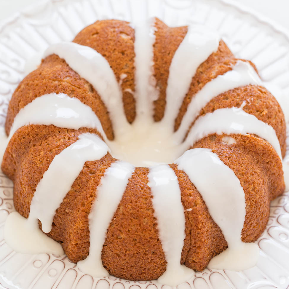 A bundt cake with white glaze on a decorative plate.