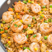 A close-up of shrimp fried rice with mixed vegetables in a pan.