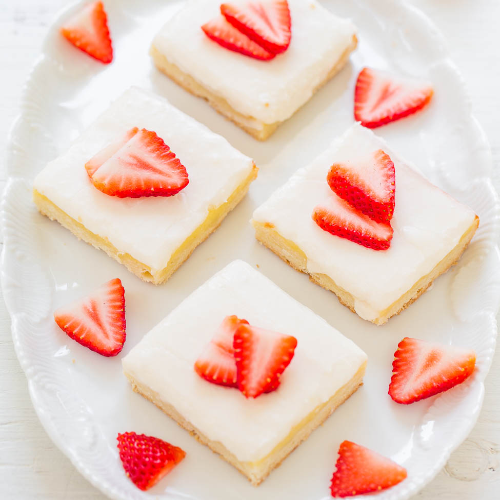 Plate of frosted lemon bars topped with strawberry slices.