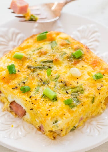 A slice of ham and green onion frittata on a white plate.