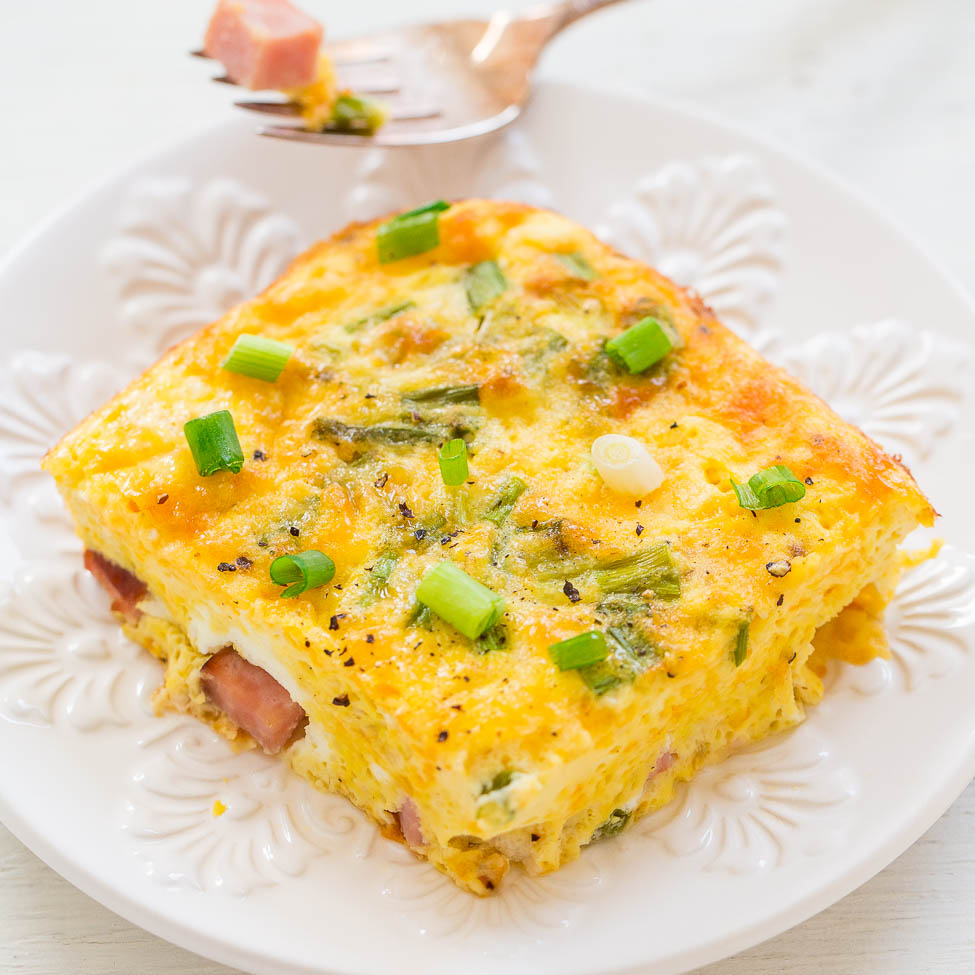 A slice of ham and green onion frittata on a white plate.