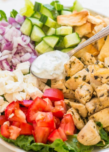 A colorful chicken salad with diced vegetables and a side of pita chips.