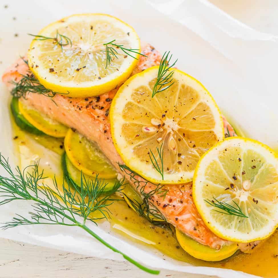 Baked salmon garnished with lemon slices and dill on a bed of zucchini.