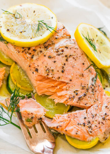 Baked salmon fillet with lemon slices and dill on a bed of zucchini.