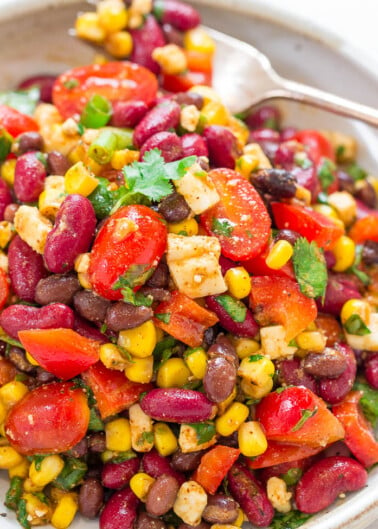 A plate of colorful bean and corn salad garnished with fresh cilantro.
