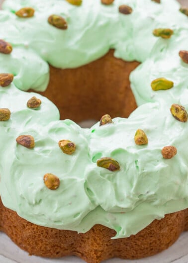 A bundt cake with green frosting and scattered pistachios on top.