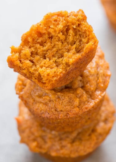Three stacked pumpkin muffins with the top one broken in half.