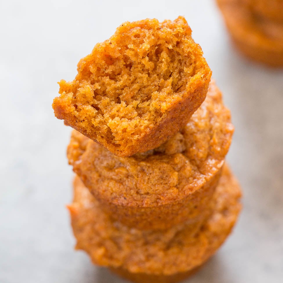 Three stacked pumpkin muffins with the top one broken in half.