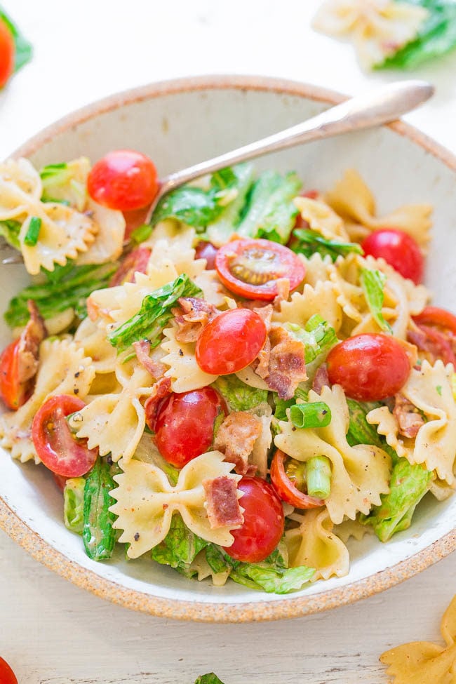 A white bowl filled with a fork and BLT Pasta Salad