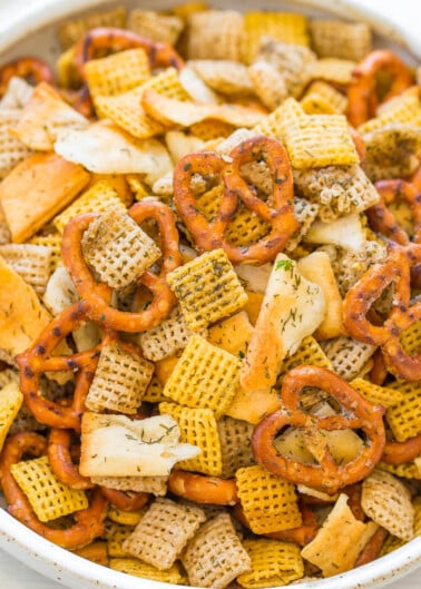 Bowl of assorted snack mix including pretzels, chex cereal, and seasoning.