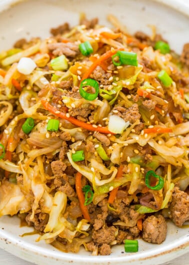 A bowl of stir-fried ground meat and vegetables garnished with green onions and sesame seeds.