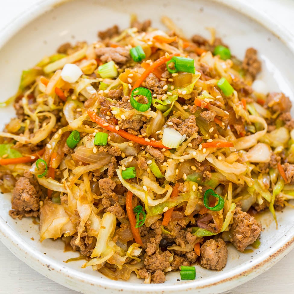 A bowl of stir-fried ground meat and vegetables garnished with green onions and sesame seeds.