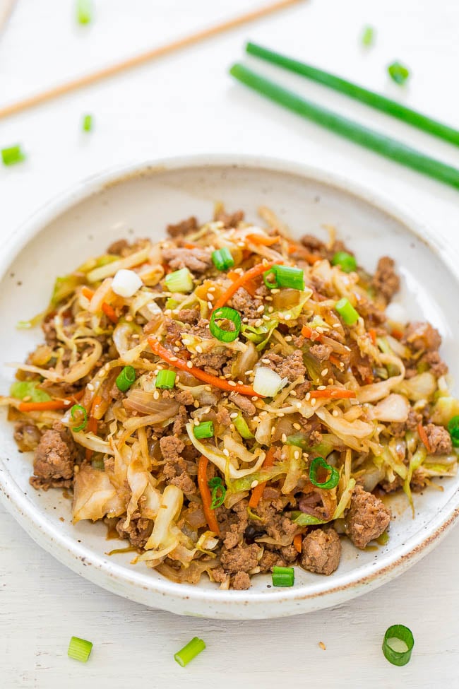Stir-fried noodles with ground meat, shredded vegetables, and garnished with sesame seeds and sliced green onions.