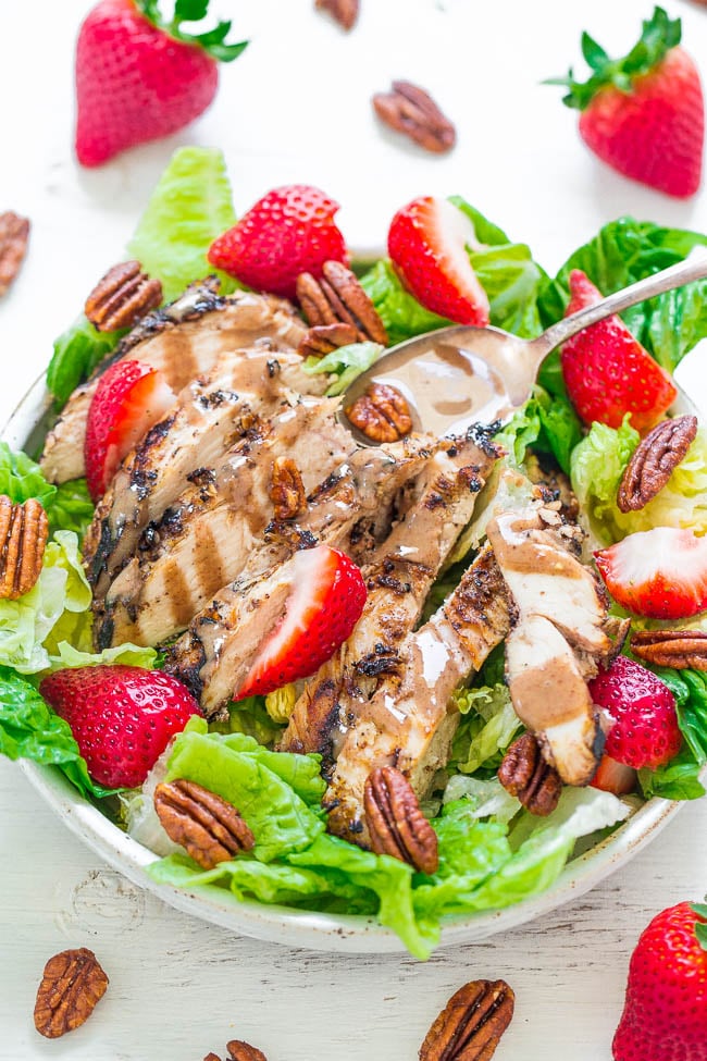 strawberry chicken salad in large bowl surrounded by pecan halves and fresh strawberries 