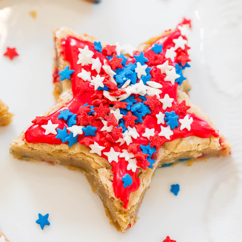 A star-shaped cookie decorated with red icing and blue and white star sprinkles.