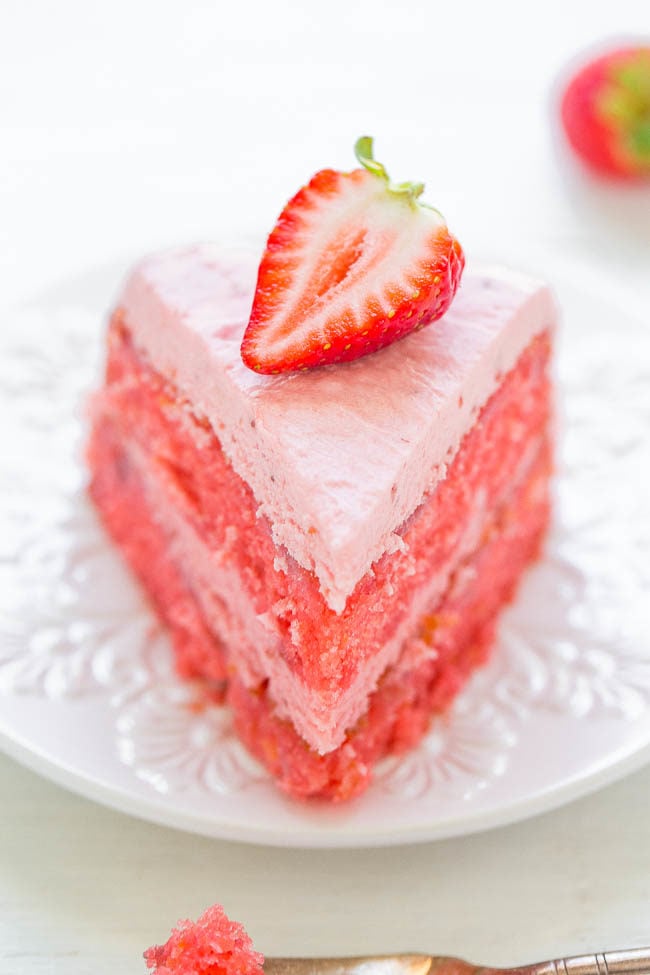 One slice of Strawberry Layer Cake with Strawberry Frosting on white plate