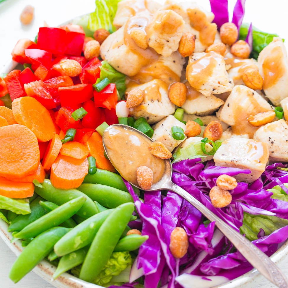 A vibrant salad with chicken, mixed vegetables, peanuts, and a creamy dressing.